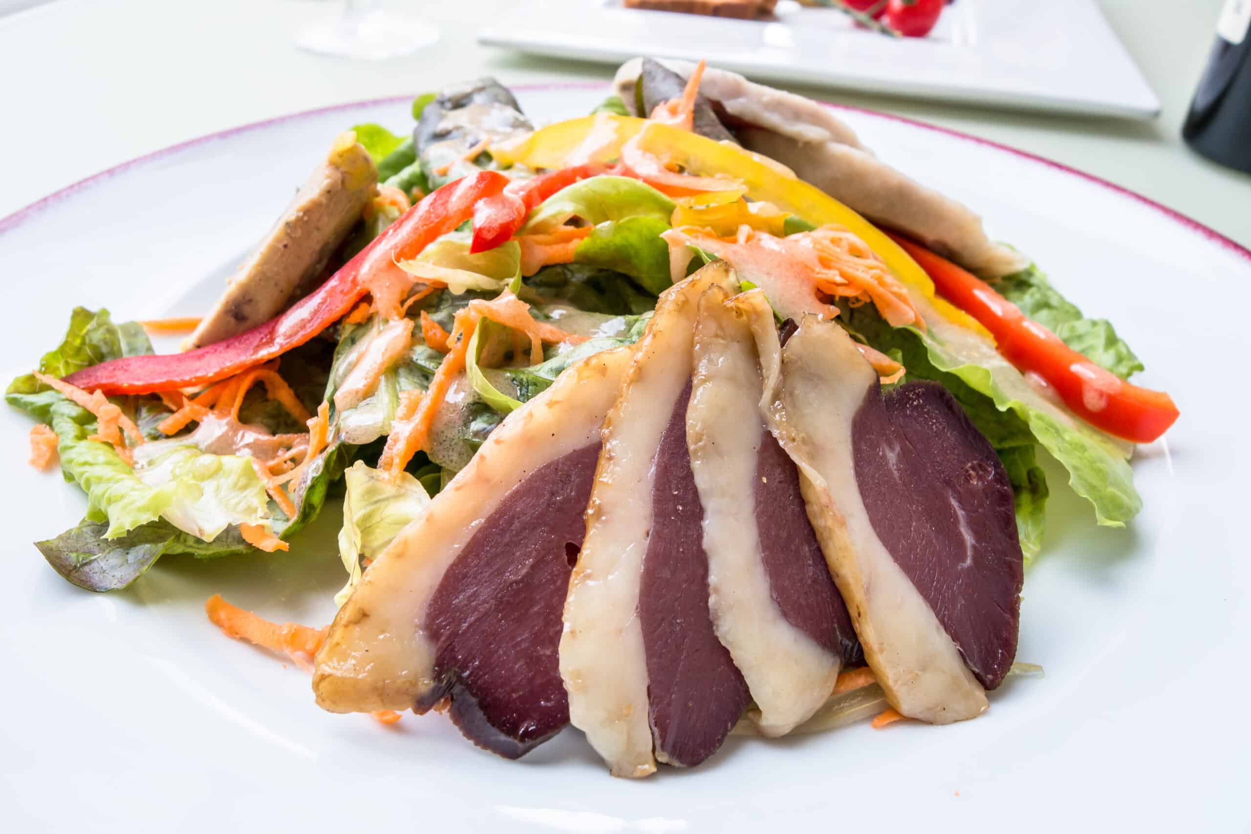 Salade gourmande avec tranches fines de magret de canard fumé, laitue, carottes râpées et lanières de poivrons.