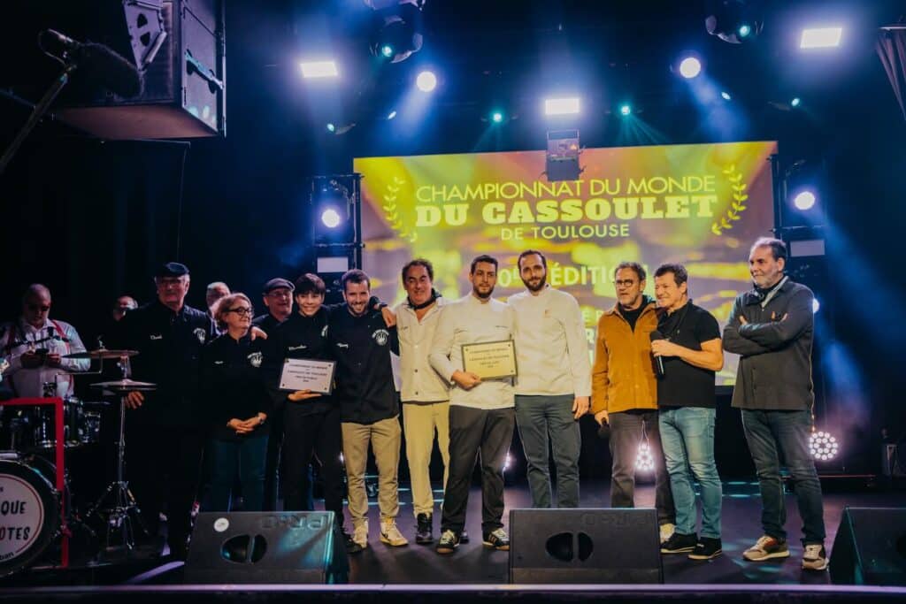 Cérémonie du Championnat du Monde du Cassoulet de Toulouse. Chefs souriants reçoivent les prix du jury et du public sur scène.